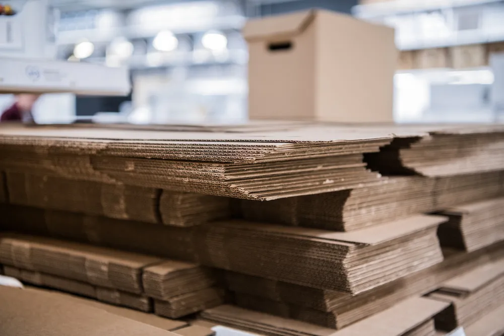 Pilas de láminas de cartón corrugado listas para convertirse en cajas y empaques de cartón en una fábrica.